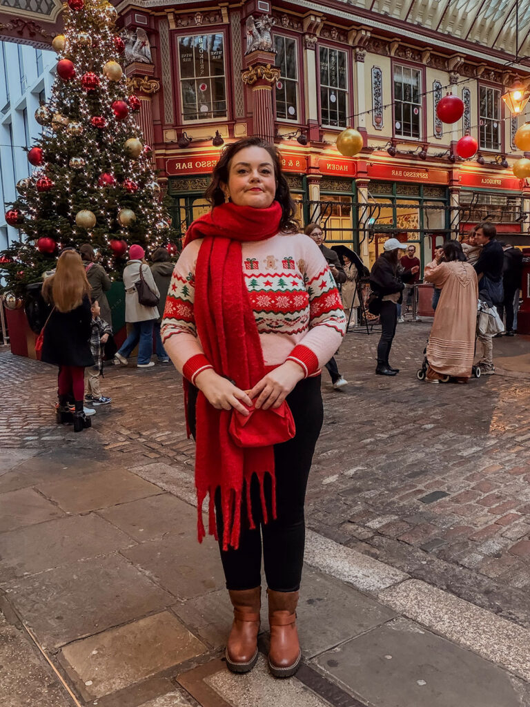 Rosie Parsons, brand photographer and business blogger, standing at Leadenhall Market in London demonstrating common Christmas photo mistakes. The shot shows a busy background with other shoppers visible, illustrating what to avoid when planning a christmas aesthetic photoshoot.